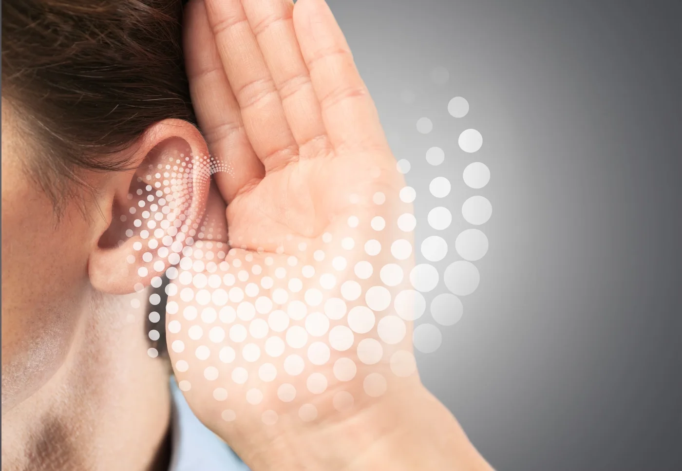A person cupping a hand to the ear to listen, illustrating everyday auditory wellness with Tinizen